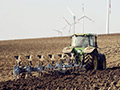 Traktor pflügt Acker, Windkraftanlagen im Hintergrund